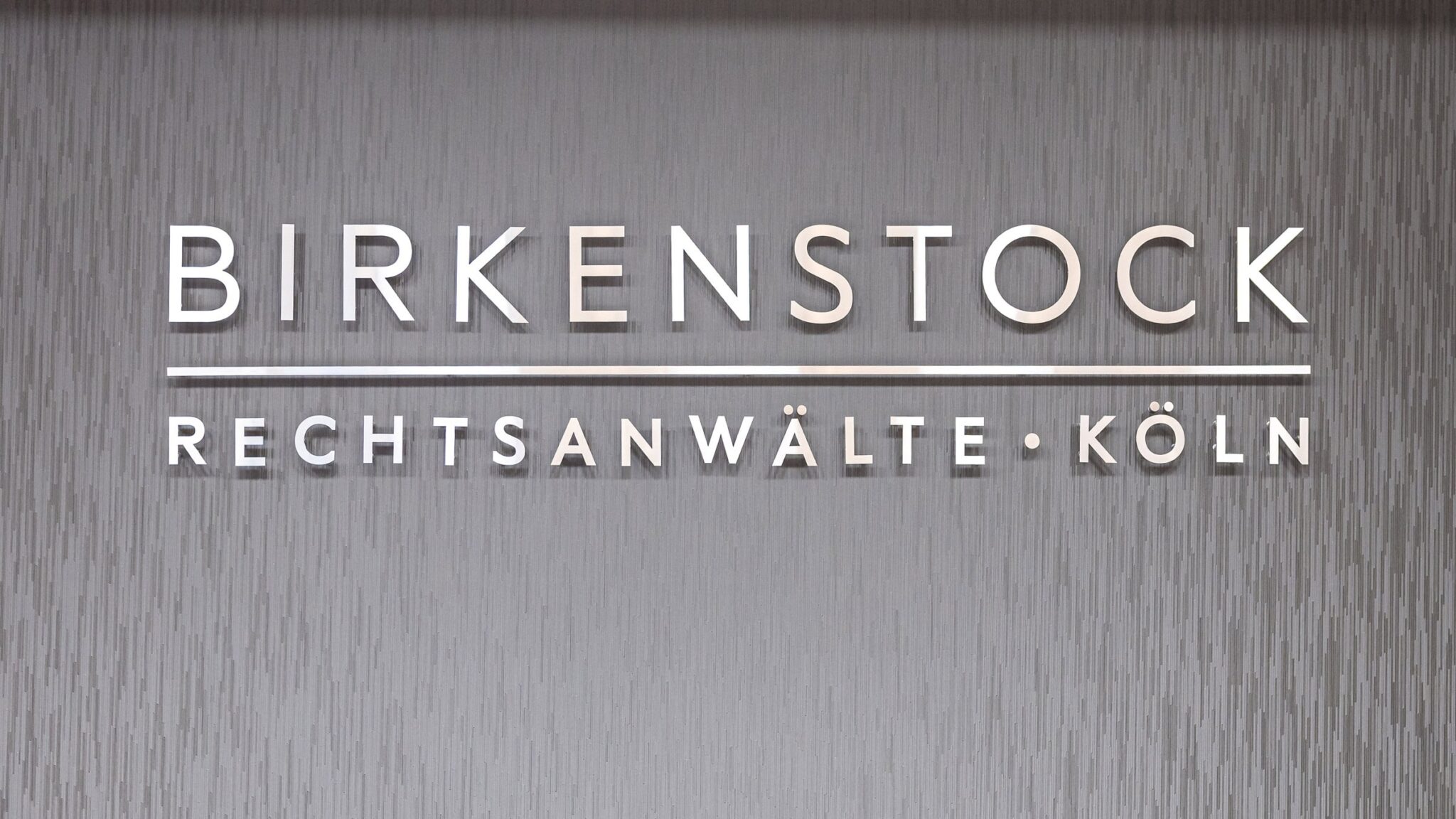 Der hochwertige 3D-Schriftzug von Birkenstock Rechtsanwälte • Köln an der strukturierten Wand im Empfangsbereich unserer Fachanwaltskanzlei für Strafrecht.