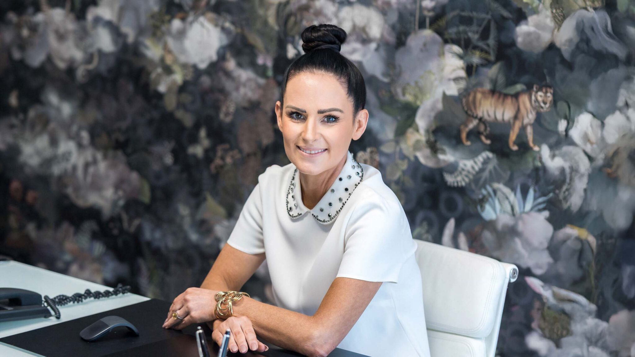 Fachanwältin für Strafrecht Jordana Bücher von Birkenstock Rechtsanwälte sitzt lächelnd an ihrem Schreibtisch und berät Mandanten.