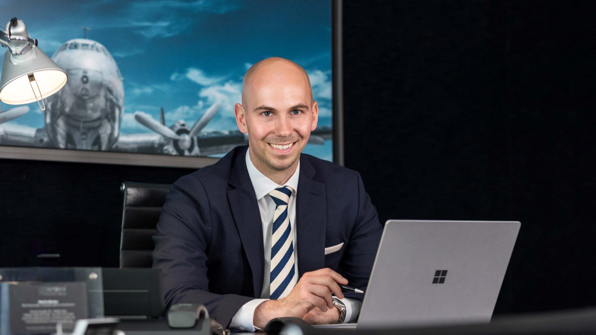 Fachanwalt für Strafrecht Jonas Bau von Birkenstock Rechtsanwälte sitzt lächelnd an seinem Schreibtisch und berät Mandanten.